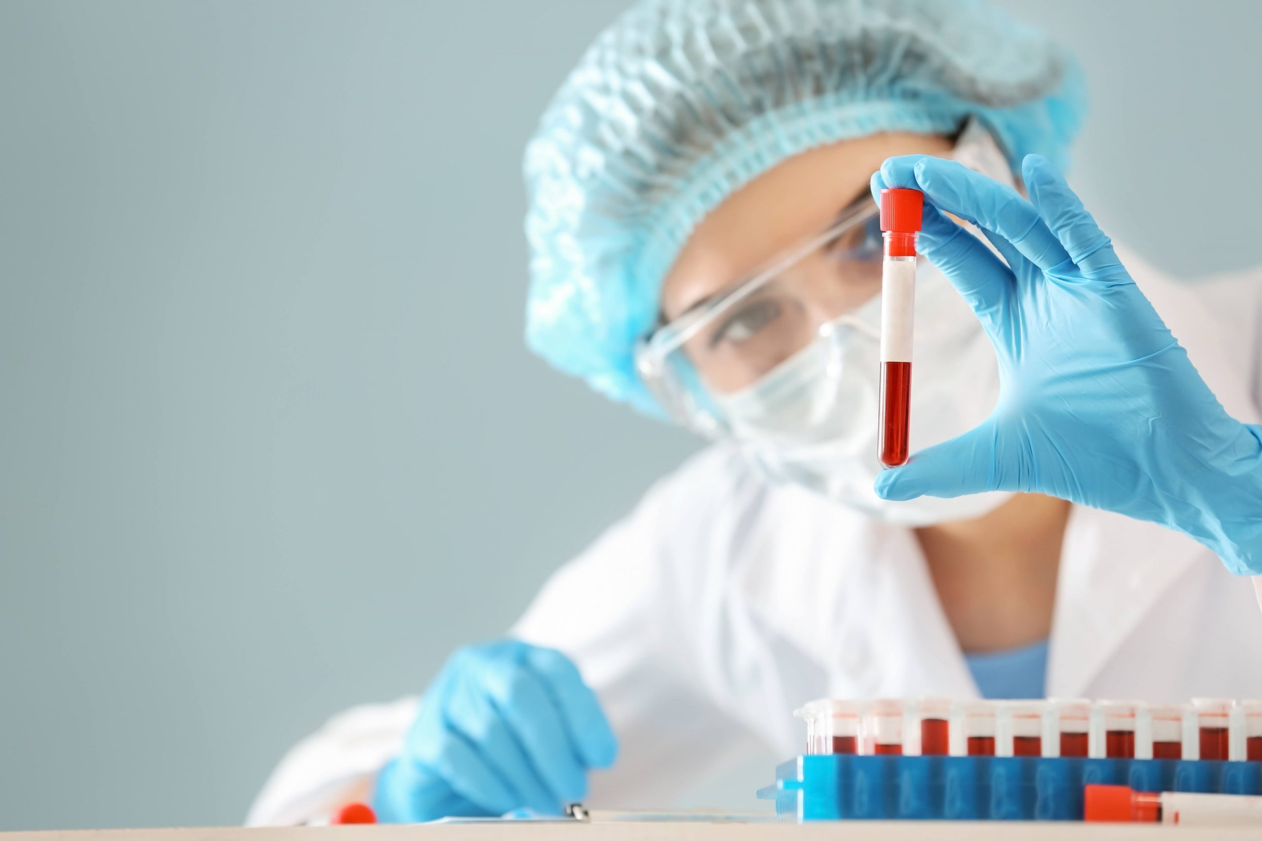 lab technician holding up a vile of blood and examining it