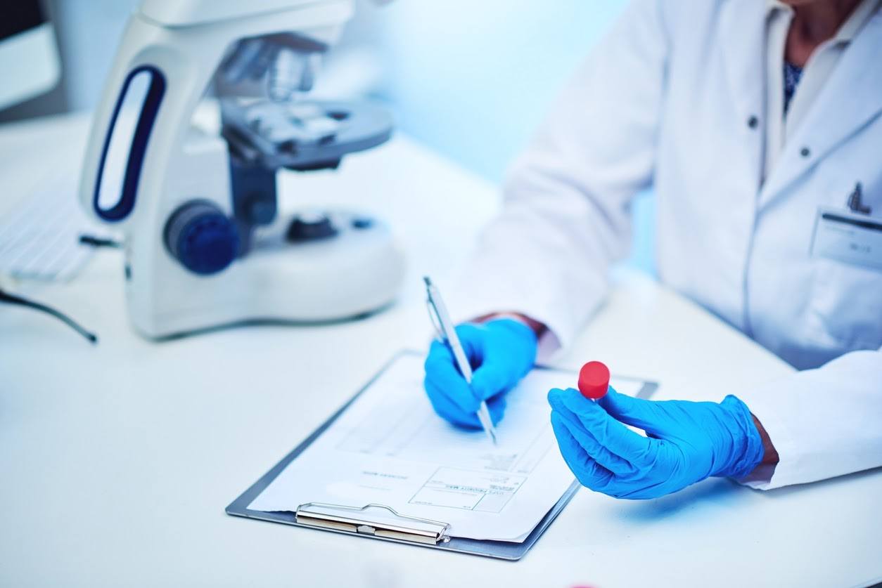 Lab technician holding a blood sample and recording the results